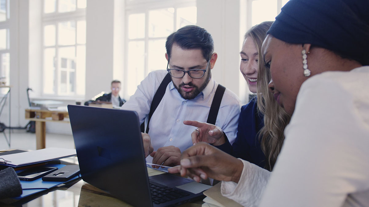 3 people sitting and looking at laptop together