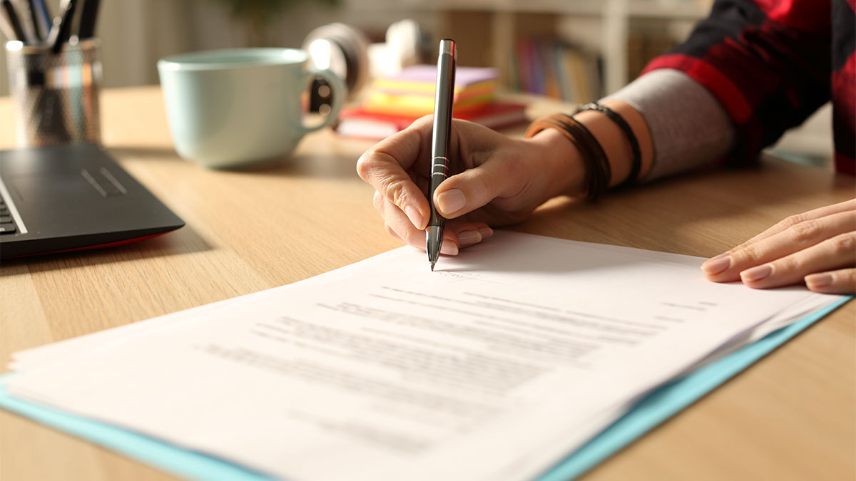 Photo of person signing documents on desk