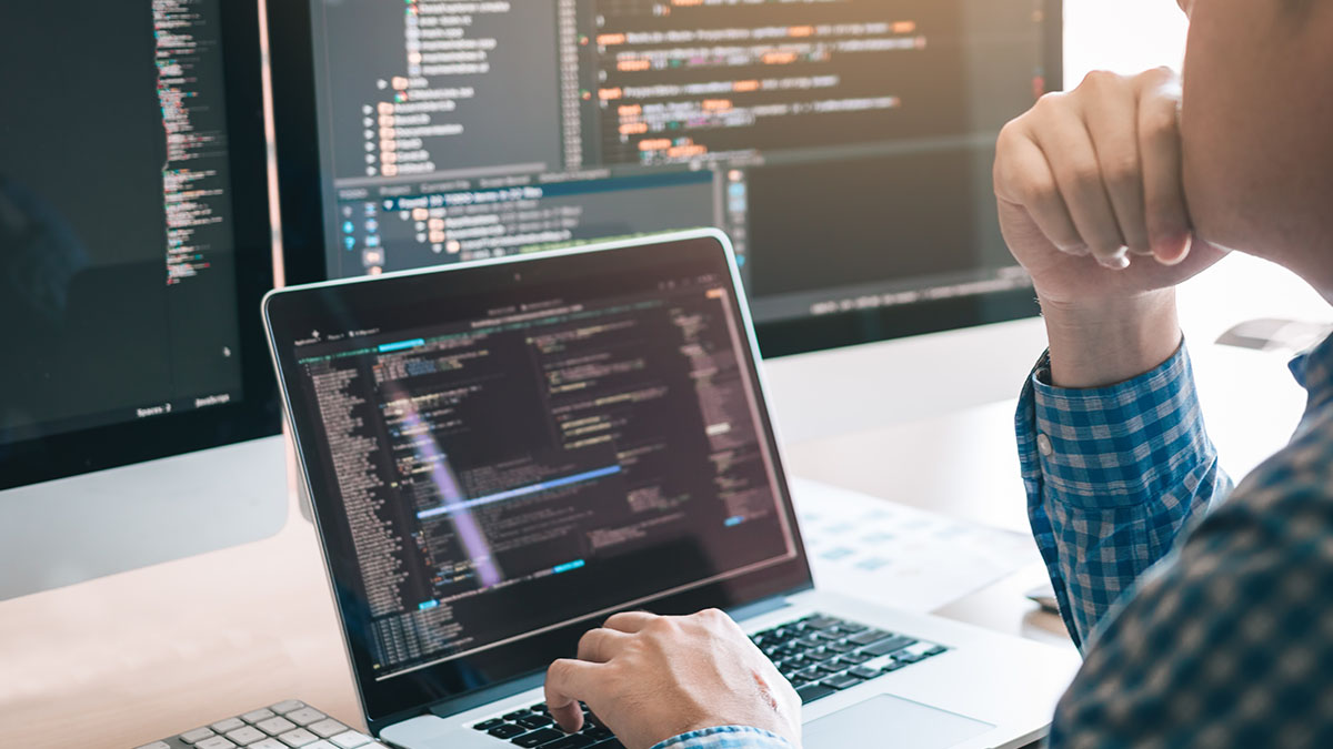 Person sitting working on code on laptop screens